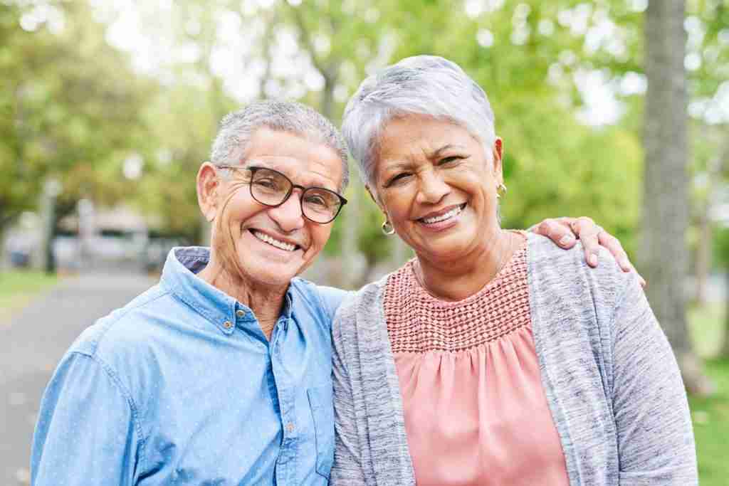 Couple smiling into the camera dealing well with symptoms of Ageing