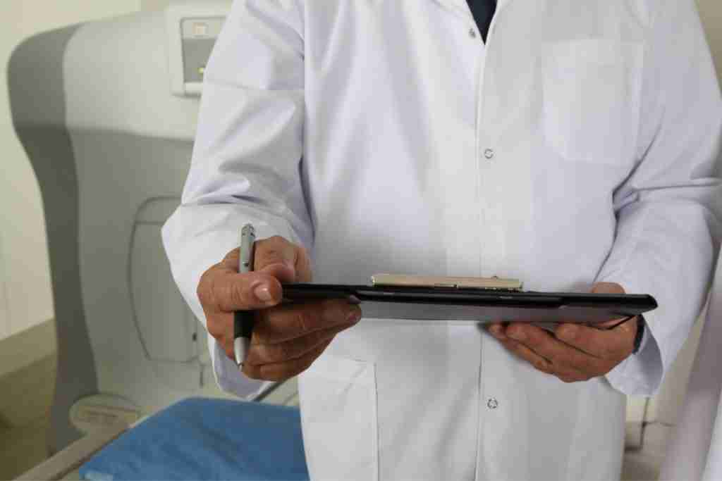 Doctor in a white coat holding a case folder discussing conventional treatment options for fibroids