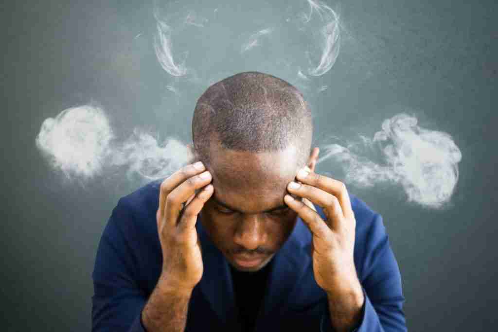 stress can effect quality of life - image of man holding forehead with smoke on both sides of the head