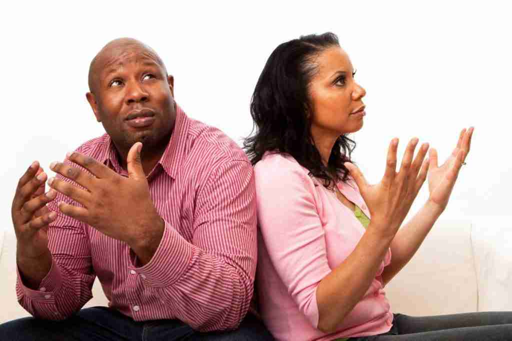 A couple seated with their backs to each other and hands raised - fights can affect relationships of people with fibroids