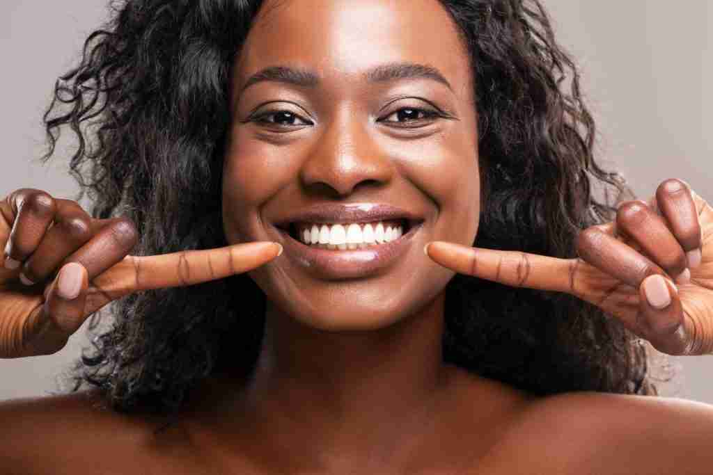 black lady with a wide smile smiling with sparkling white teeth - pain can be one of the Major Dental Warning Signs