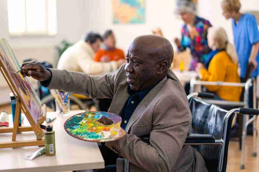 Black man in wheelchair painting - art is one of the Therapies for Powerful Self-Care