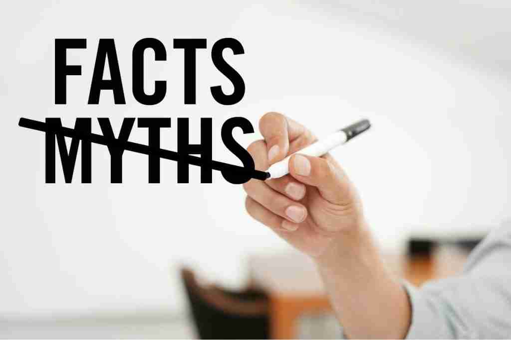 The words facst and myths are written on a board with the latter crosed out by a person's hand
