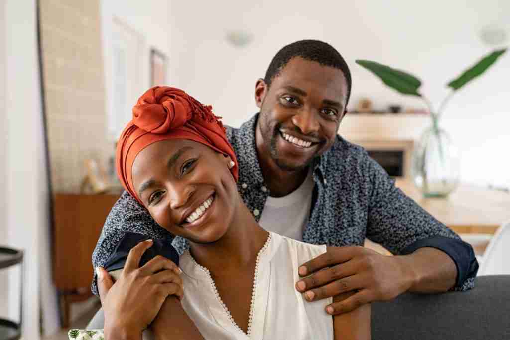 Man holding his aprtner while they both smile at the camera - support in listening and practical ways helps fibroids male perspective to grow.