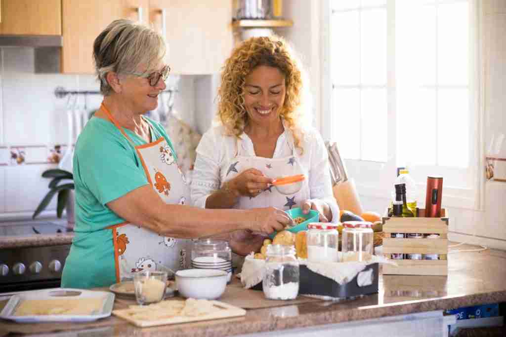 Poor nutrition can cause health issues at home - image of two ladies preparing a meal with fresh food in a well lit kitchen
