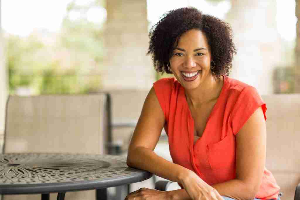 Pretty black woman in red top in a sunny outdoor garden room