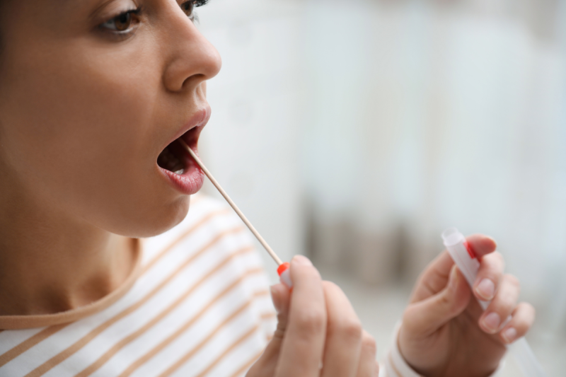 Lady placing a swab in the mouth for a saliva cortisol test
