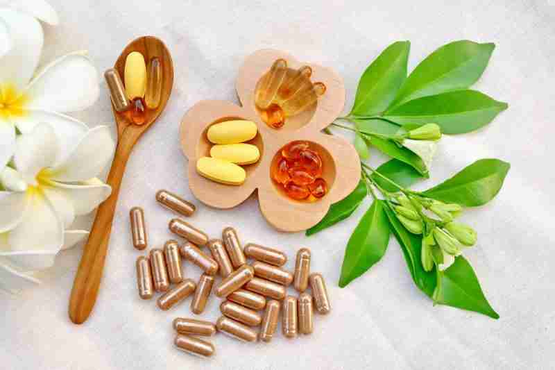 Different supplements  arranged on a wooden bowl and spoon